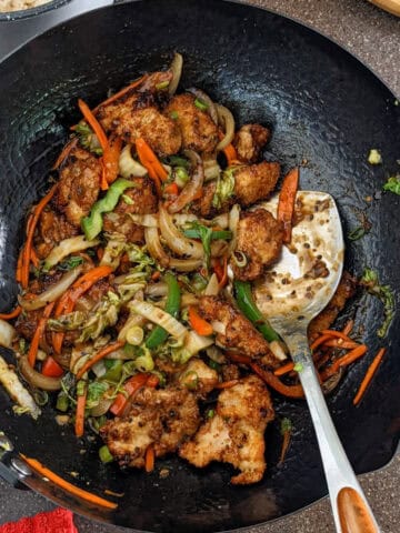 hot honey sesame chicken with juilienne vegetables in a wok