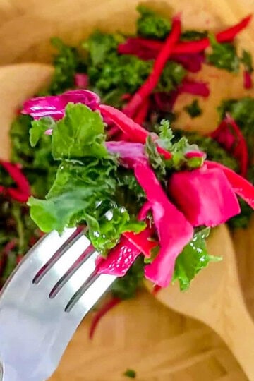 close up of massaged kale salad with pickled vegetables on a fork.