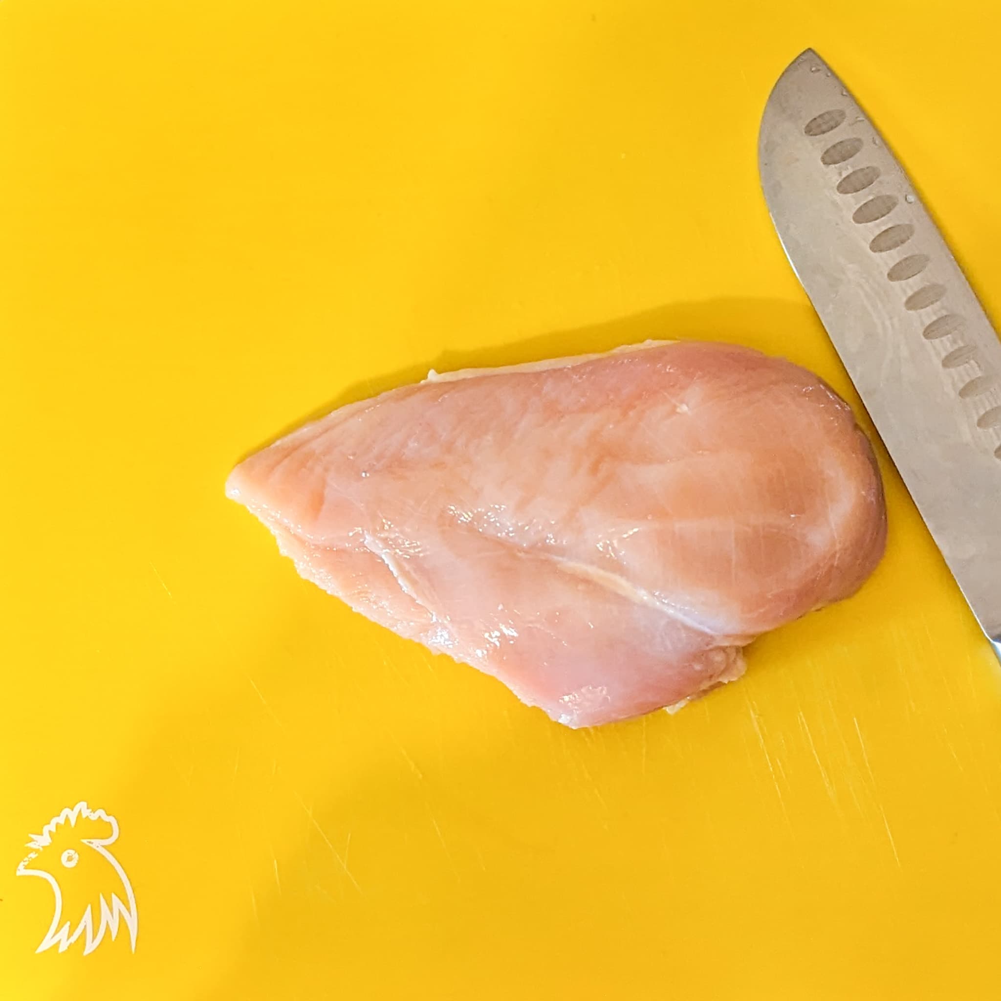 chicken breast on a cutting board  with a knife for slicing chicken cutlets