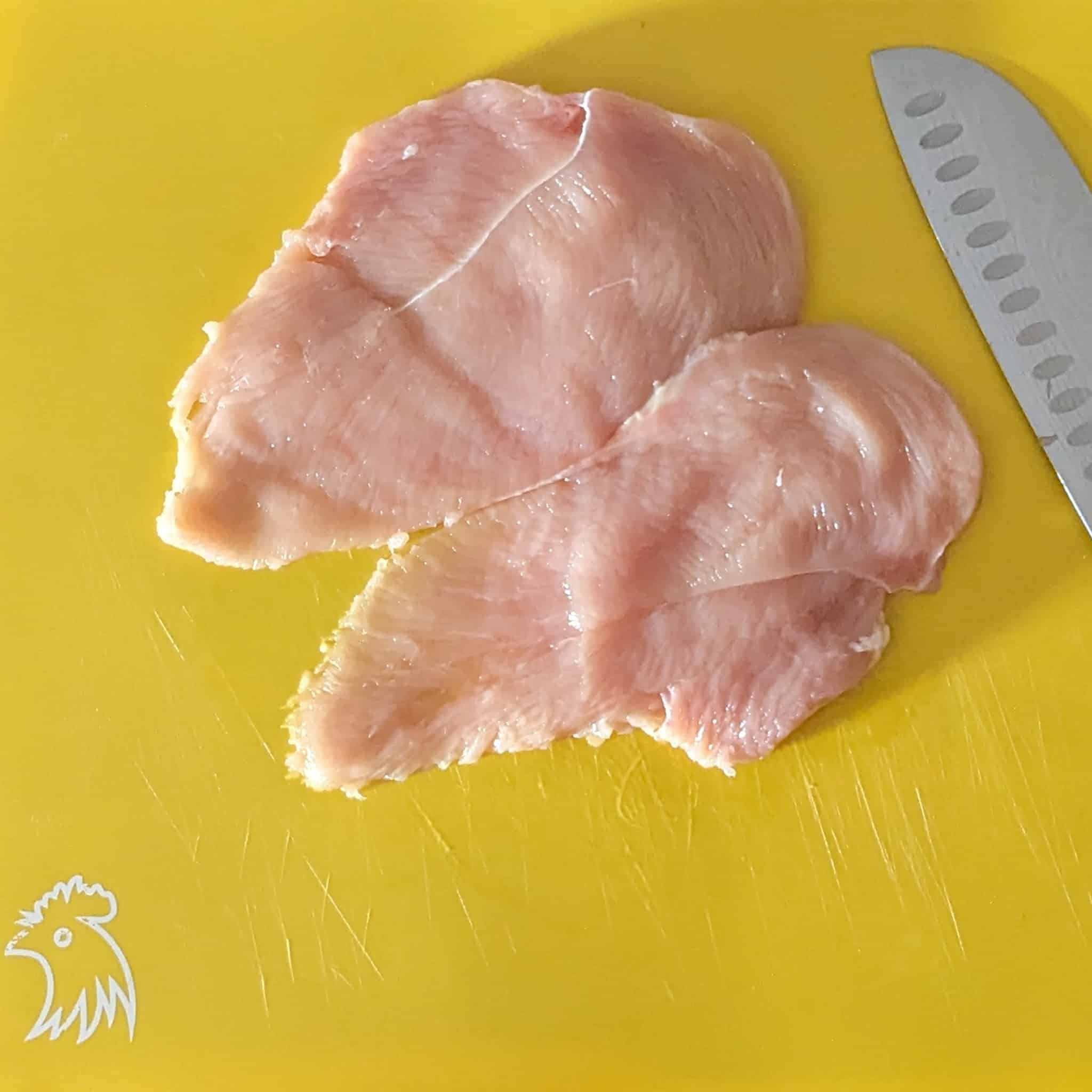 butterflied chicken breast on a color coded cutting board for raw chicken