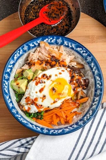 sesame chili rice bowl on a wooden board with napkins.