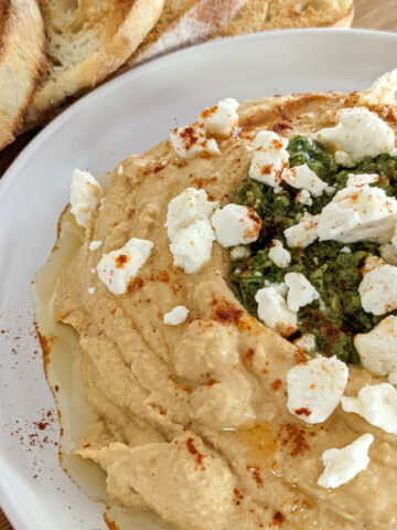 upclose picture of hummus with zhoug and feta cheese