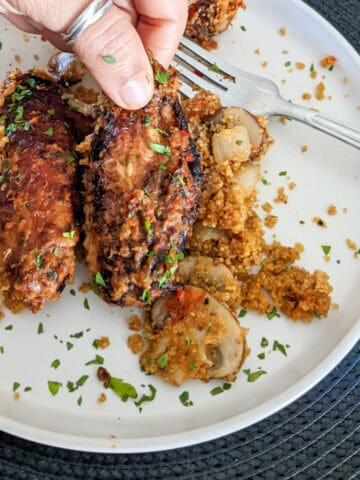 baked chicken wing in hand on plate with fonio pilaf