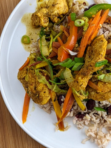 curry brown chicken breast with vegetables over coconut rice and beans