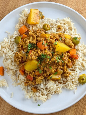 curried turkey picadillo in on brown basmati rice in a round white plate