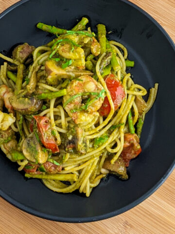 Pesto Shrimp Pasta with shrimp, tomatoes and asparagus in a black pasta bowl