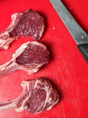 lamb chops on a cutting board with a boning knife