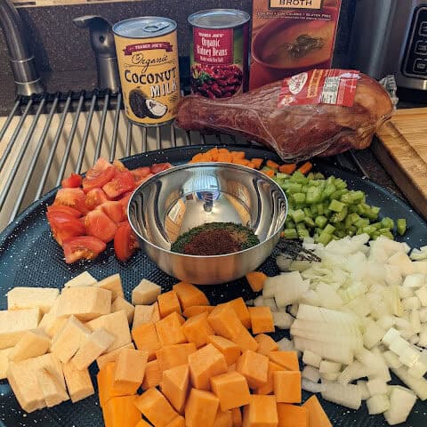 Prepped Ingredients for spicy red bean stew with whole smoked turkey, canned coconut milk, canned red kidney beans and low-sodium chicken broth in the background