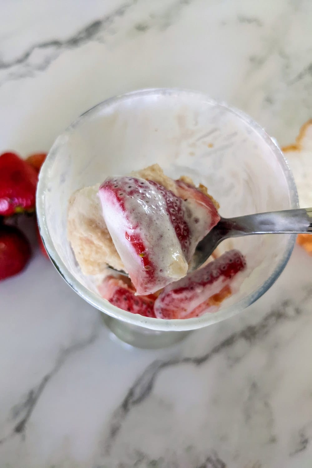 Indulgent strawberry banana shortcake layered with creamy ice cream in a stylish glass dish.