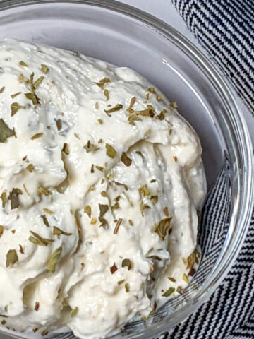 Whipped garlic herbed cottage cheese in a small round glass bowl