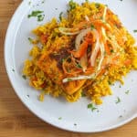 Golden spiced salmon on fluffy yellow rice with colorful slaw and cilantro garnish.