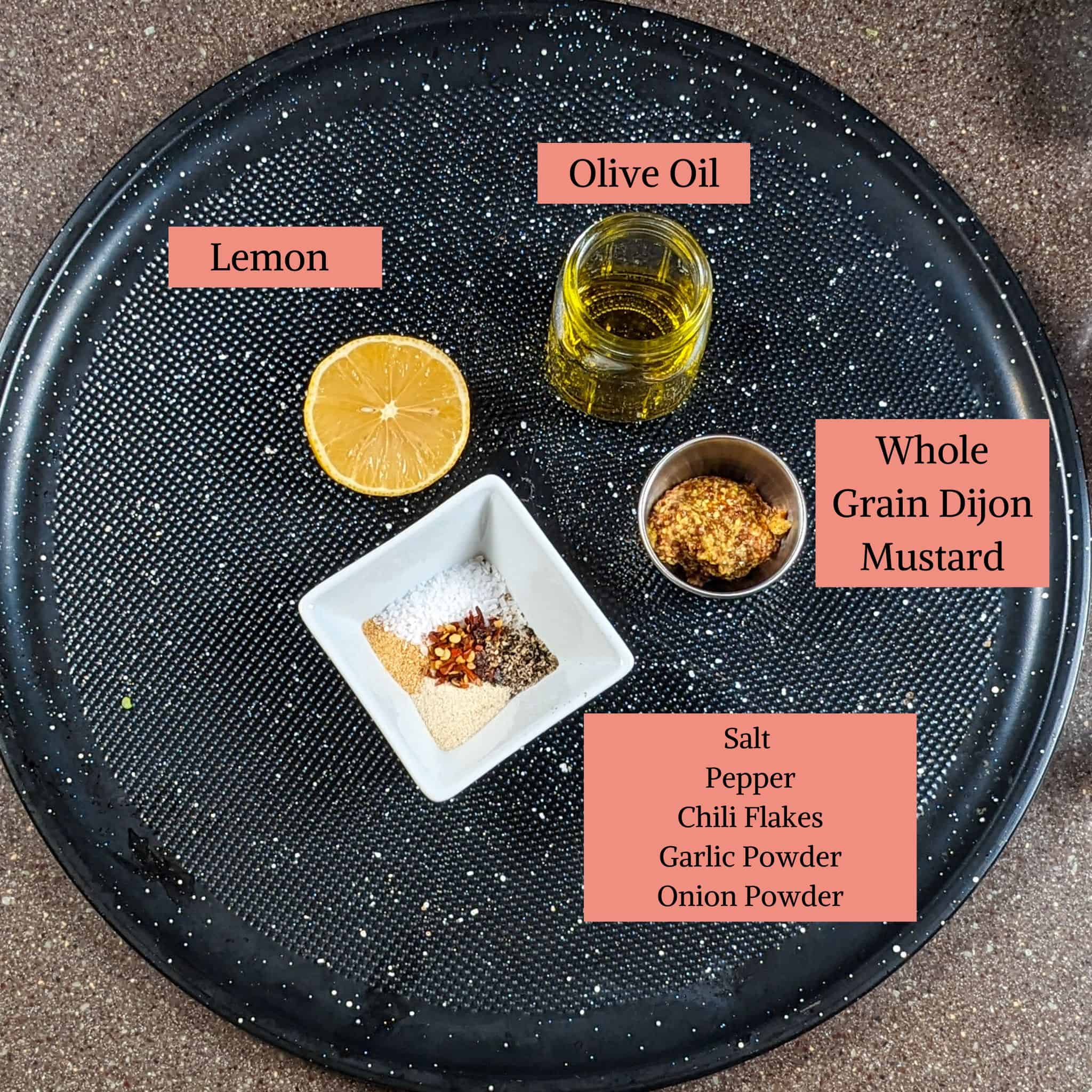 dijon mustard vinaigrette ingredients in containers on a round black pizza pan