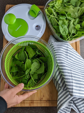salad spinner opened with baby spinach in the basket
