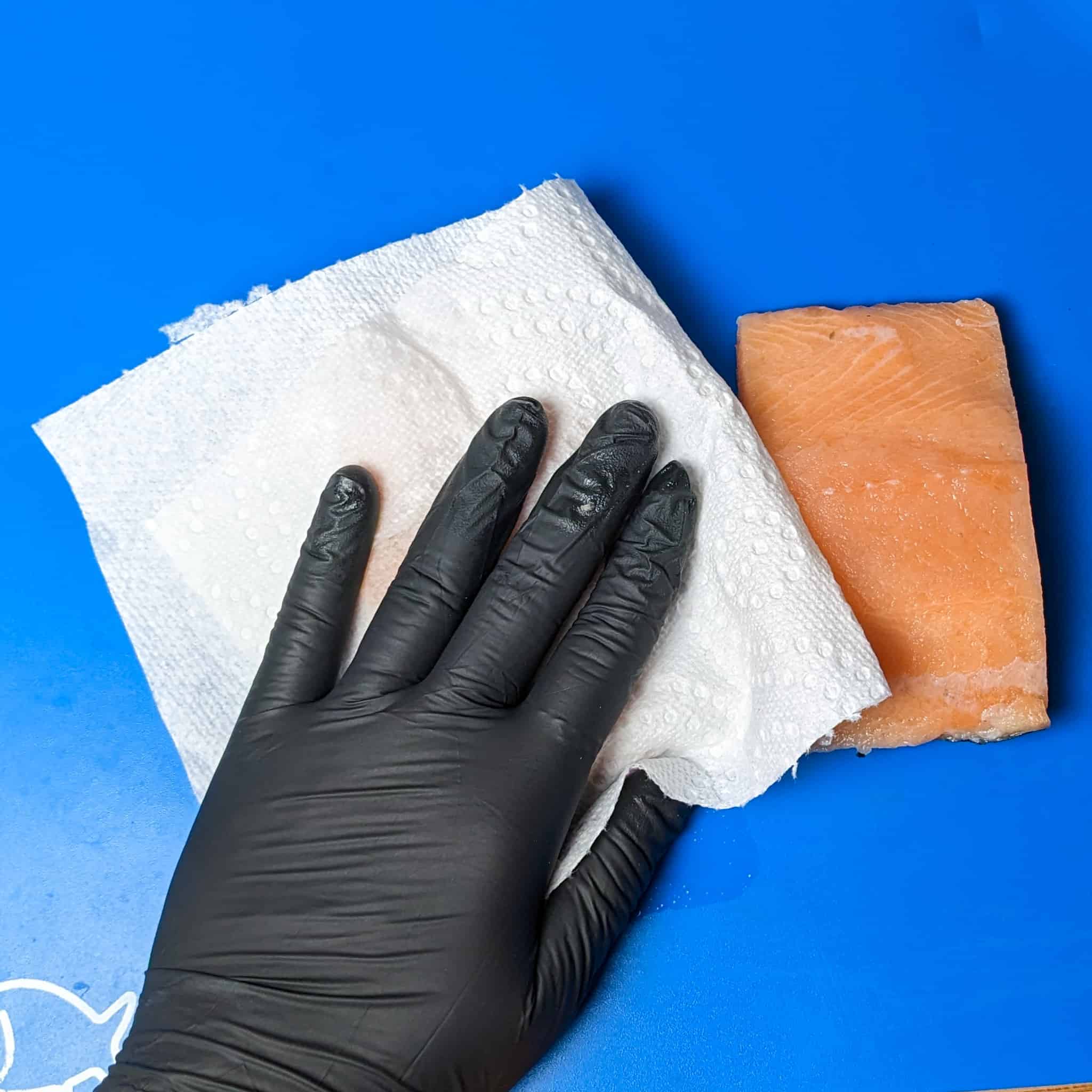 patting salmon fillet dry with paper towel.