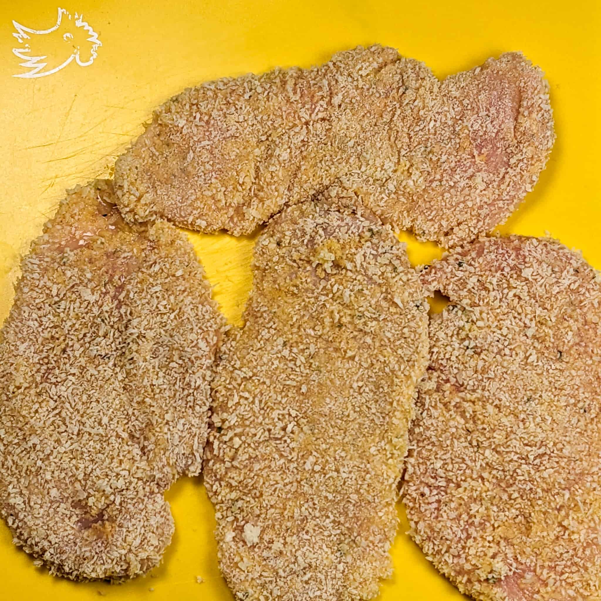 panko breaded chicken cutlets on a yellow cutting board mat