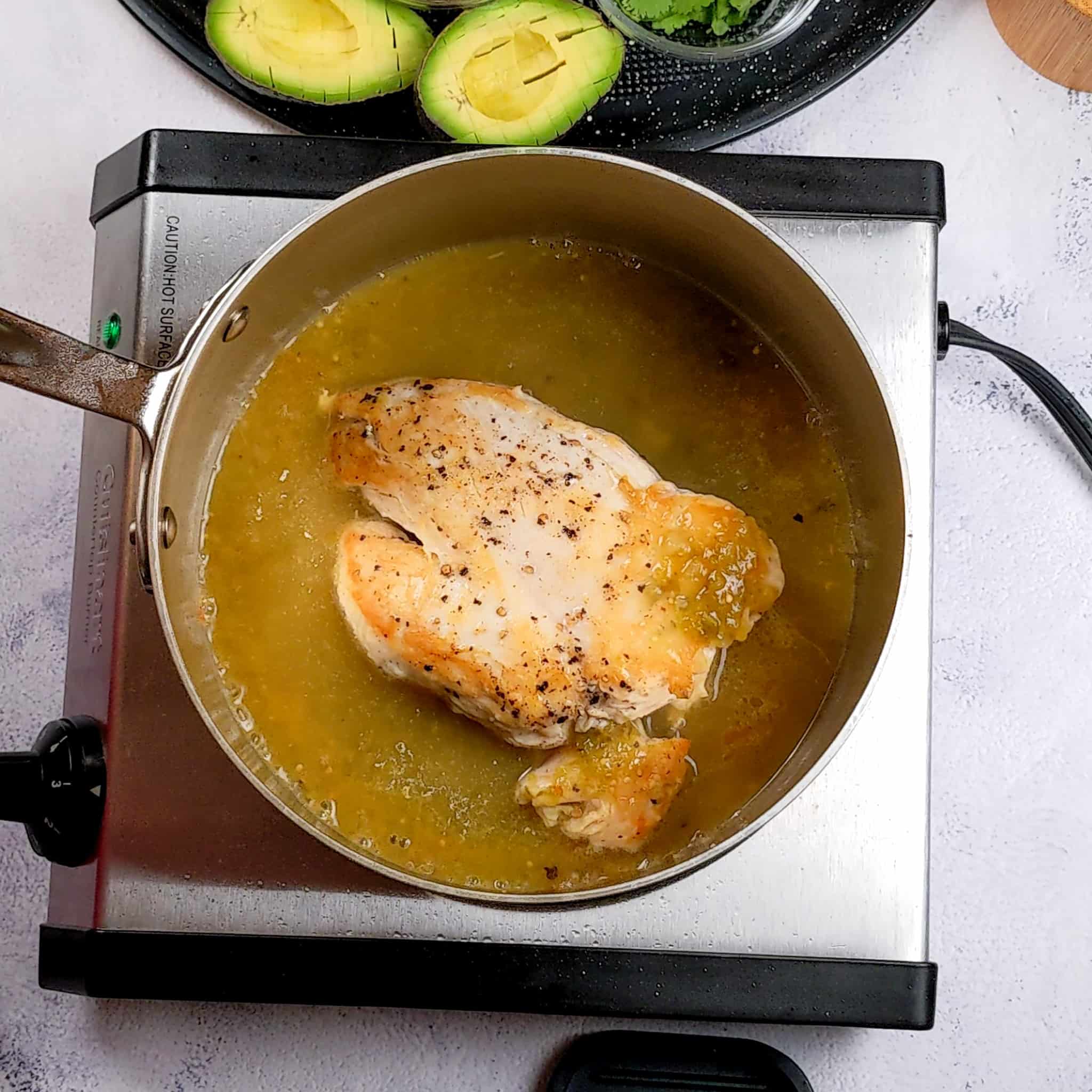 brown chicken breast in a saucepan with salsa verde chicken broth