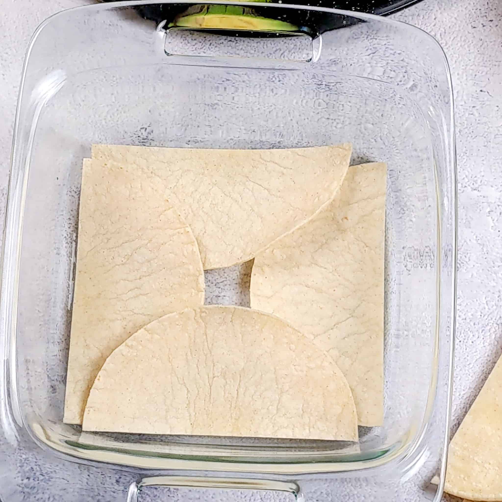 layered havled corn tortillas in an 8x8 baking dish