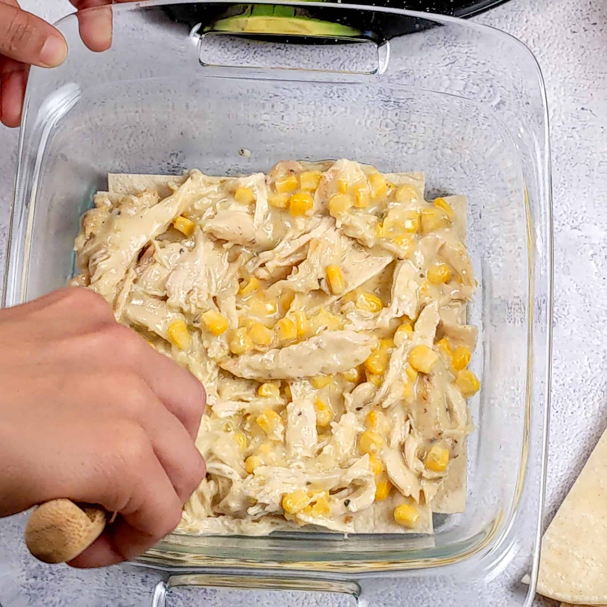 a layer of the creamy salsa verde chicken corn sauce in the 8x8 baking dish