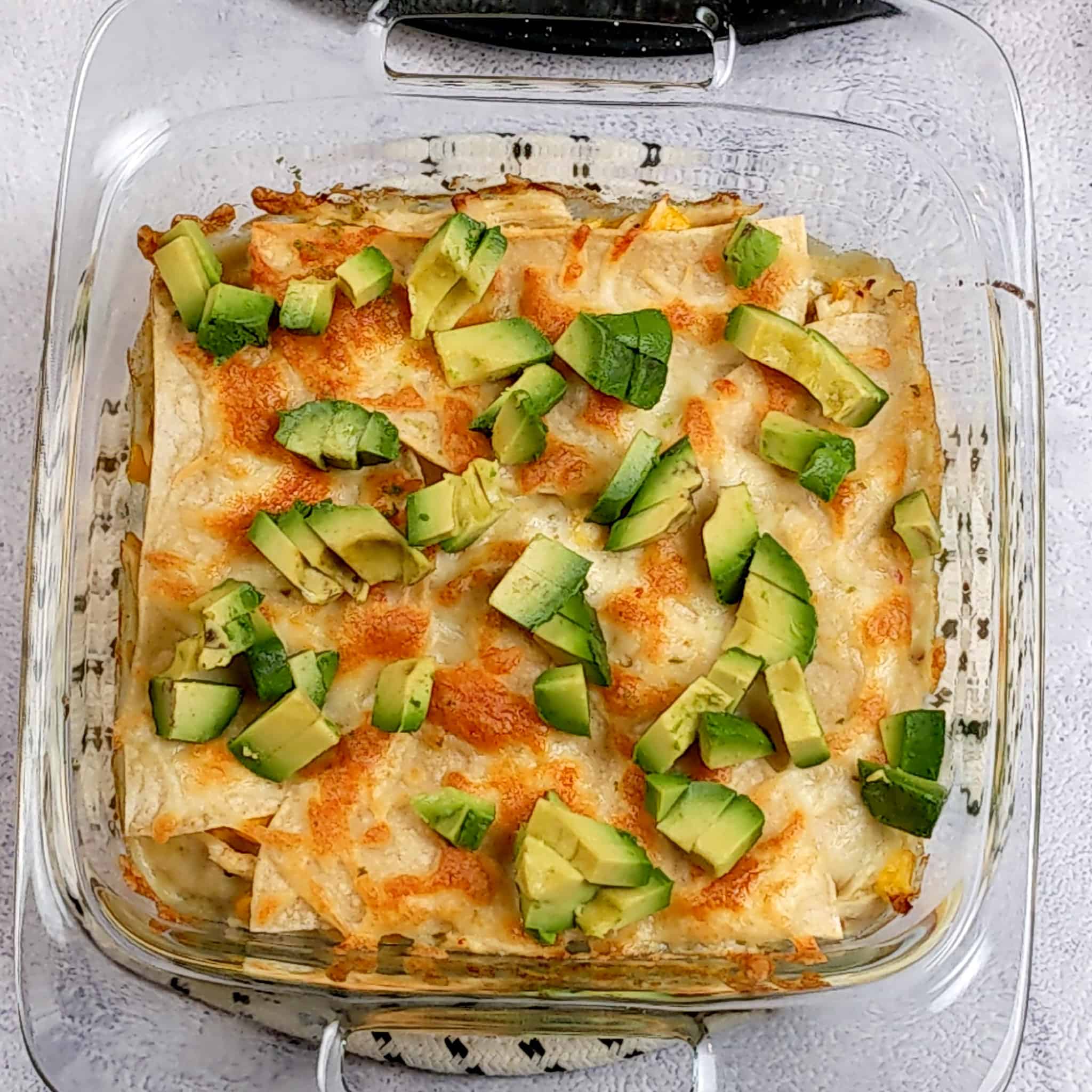 diced avocado pieces on top of the baked chicken tortilla casserole