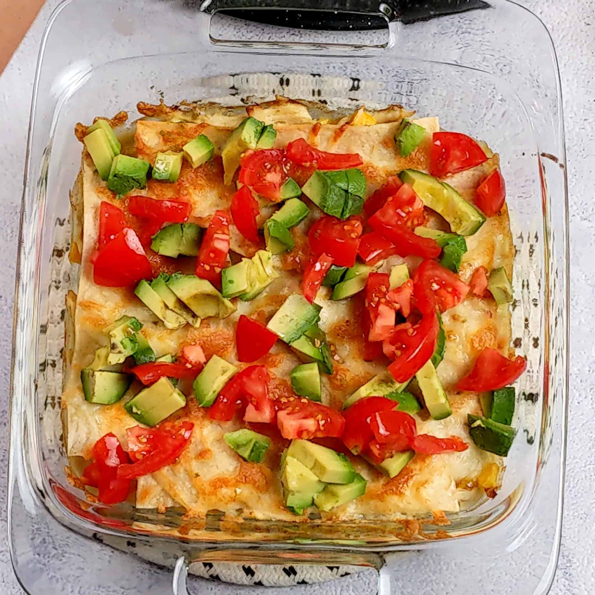 diced tomatoes, and diced avocado pieces on top of the baked chicken tortilla casserole