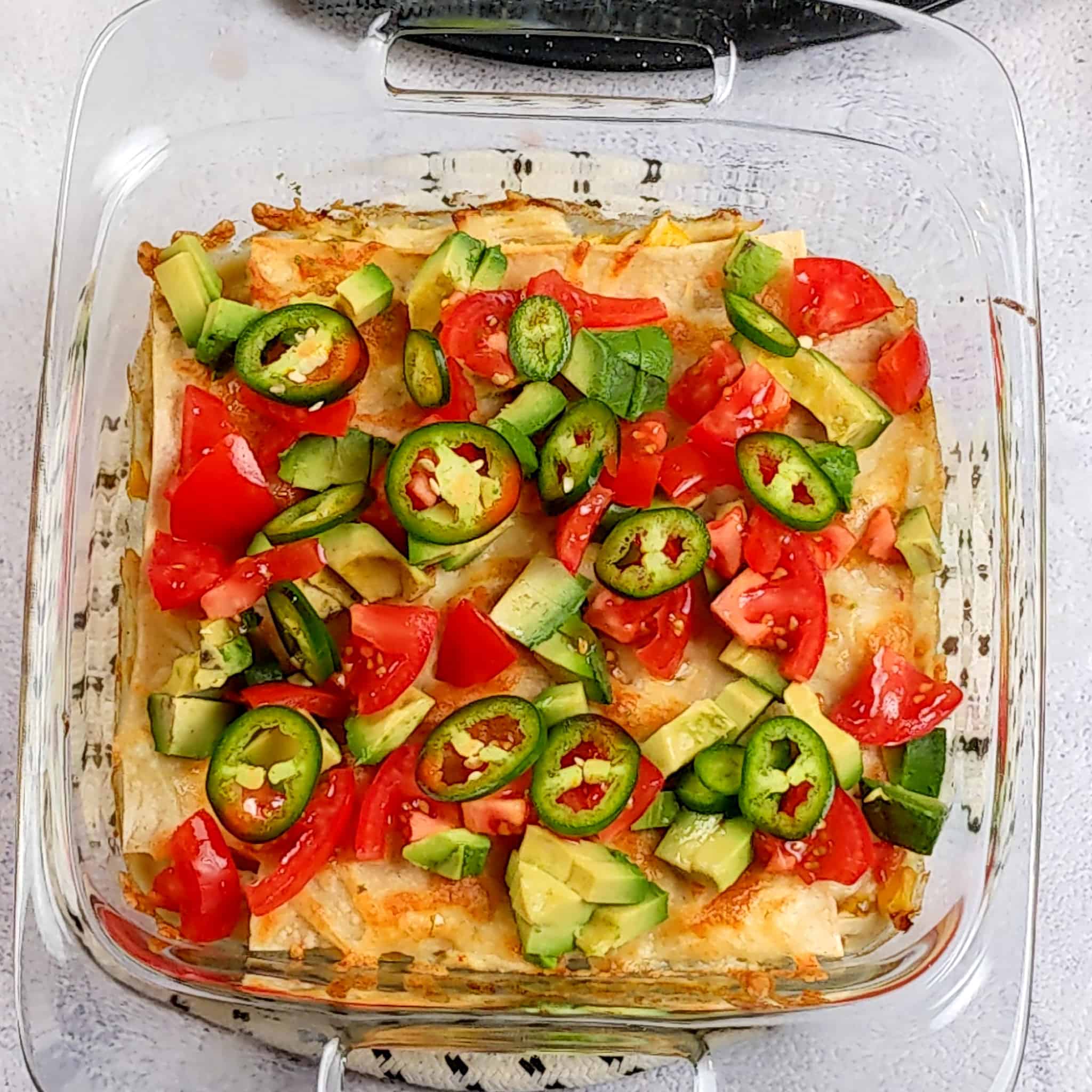sliced jalapeno rings, diced tomatoes, and diced avocado pieces on top of the baked chicken tortilla casserole