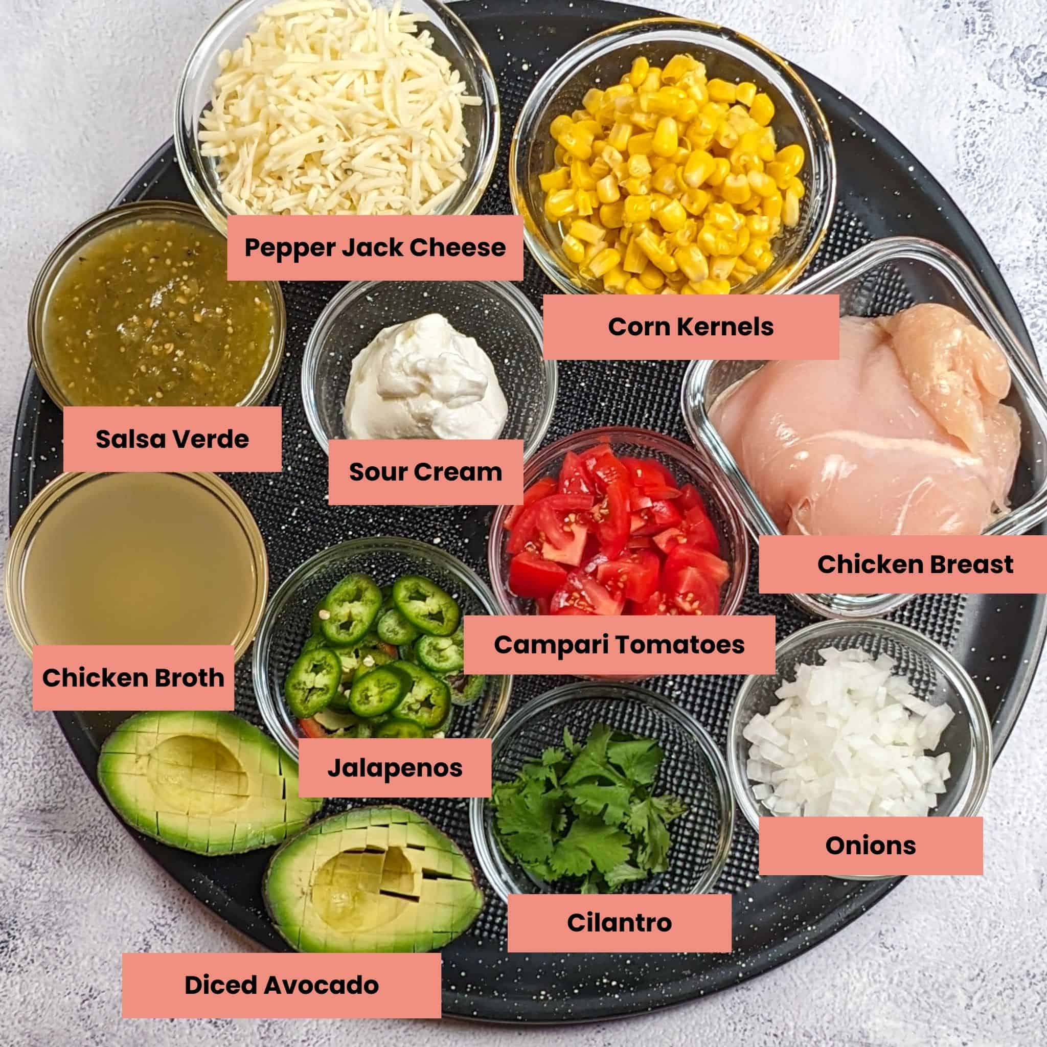 ingredients for the chicken tortilla lasagna in containers on a large round pizza pan with each ingredient labeled