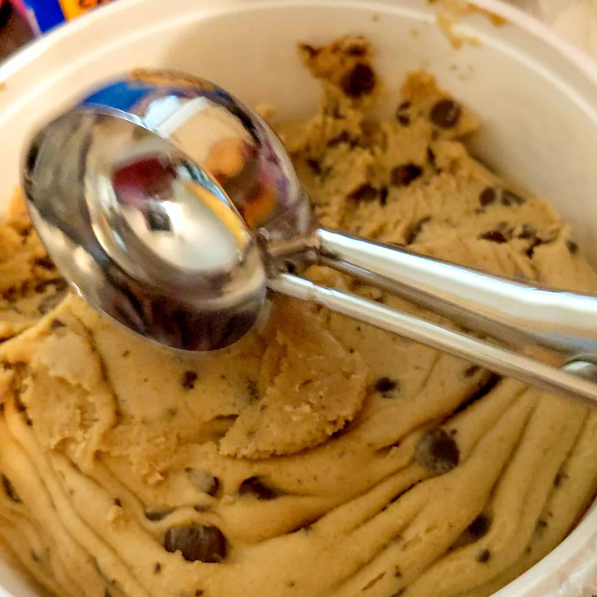 medium scooper about to scoop cookie dough in a toll house chocolate chip dough tub for the air fryer s'mores chocolate chip cookie recipe