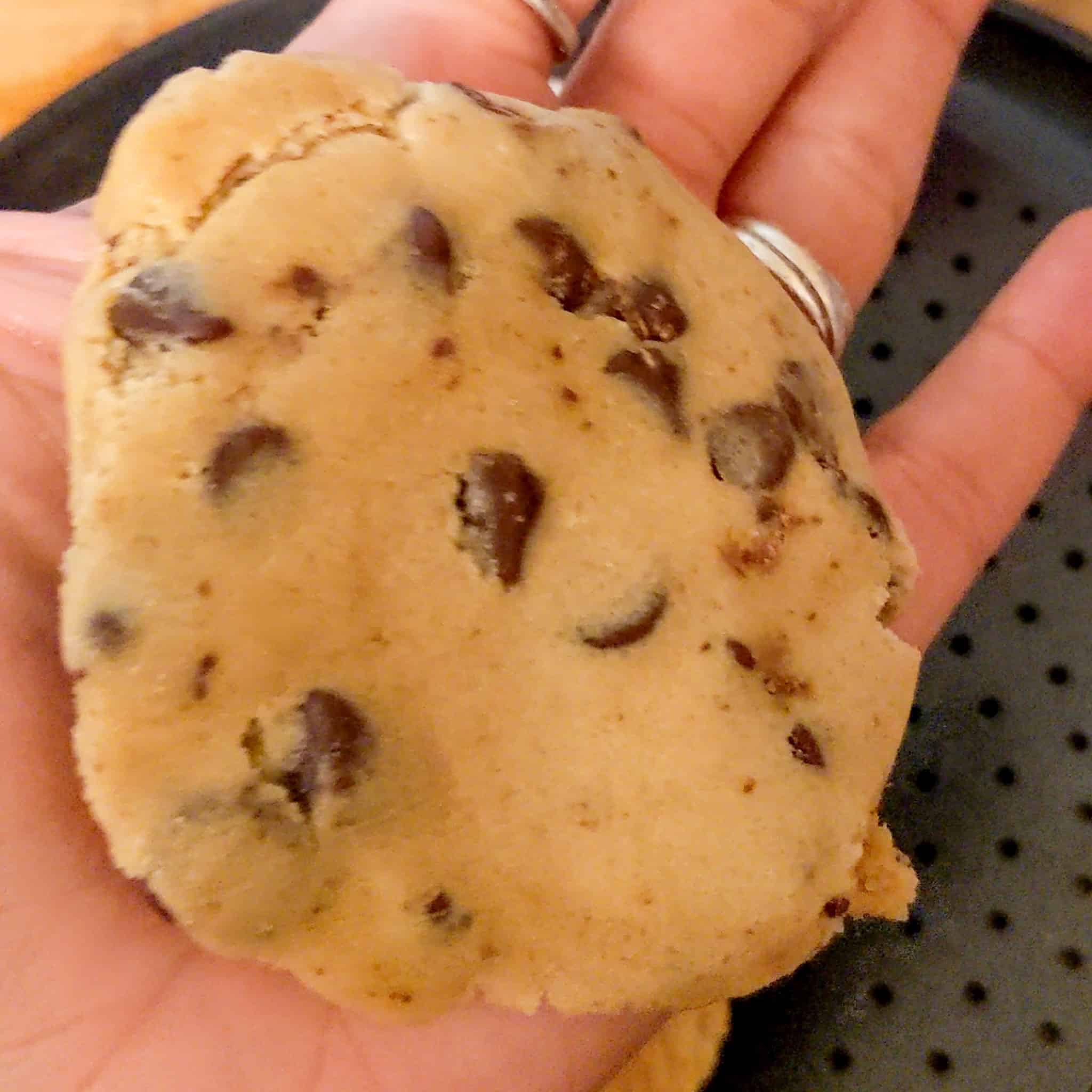 toll house chocolate chip cookie dough flatten on the palm of a hand