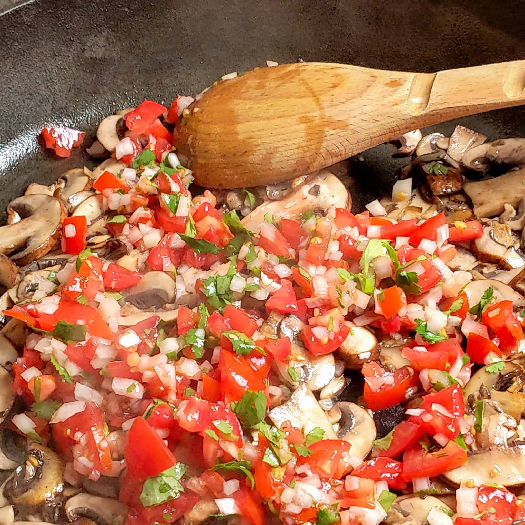 prep prepped pico de gallo vegetables added to the browned sliced mushrooms in a large wide cast iron skillet