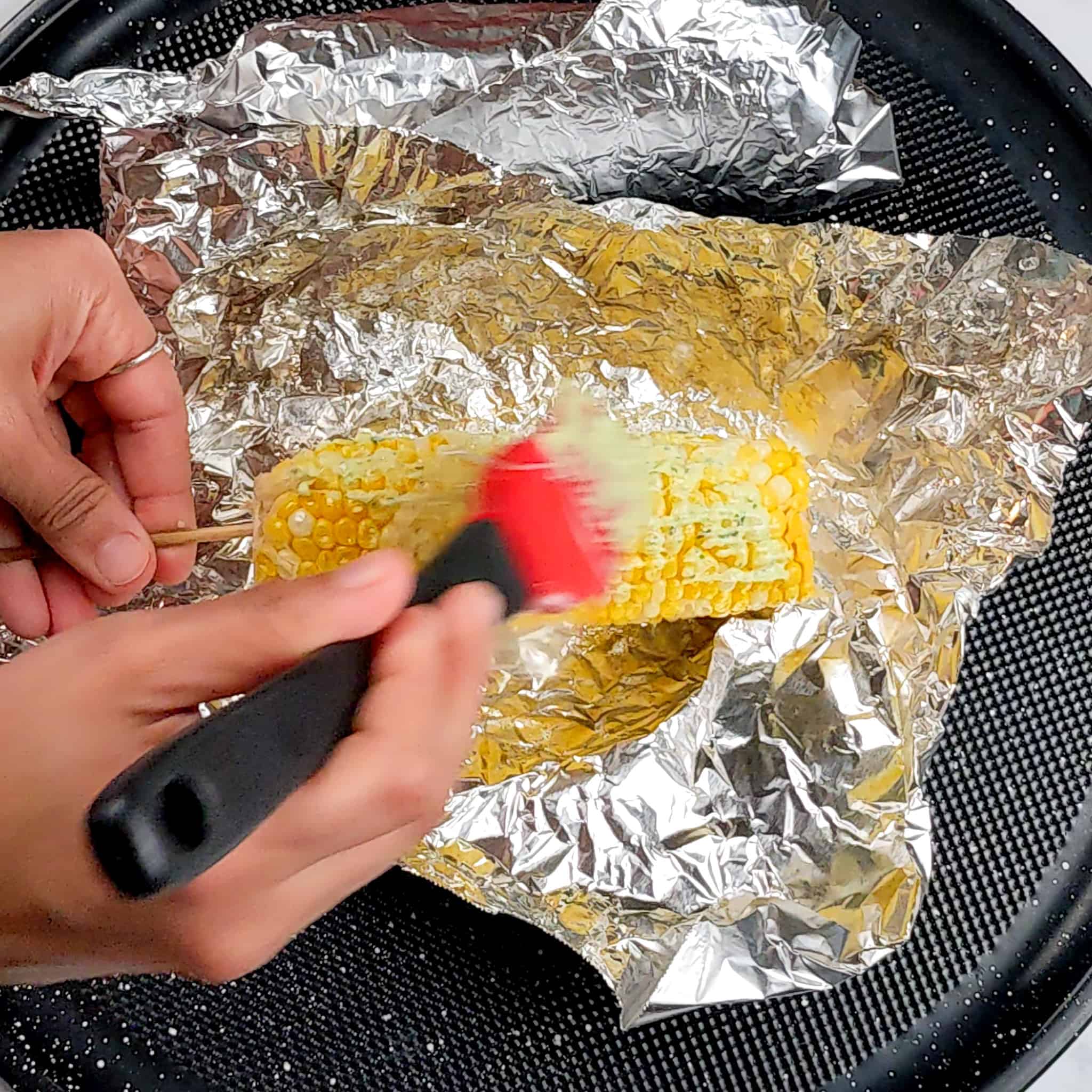 brushing corn with pesto mayo for parmesan pesto corn con the cob recipe