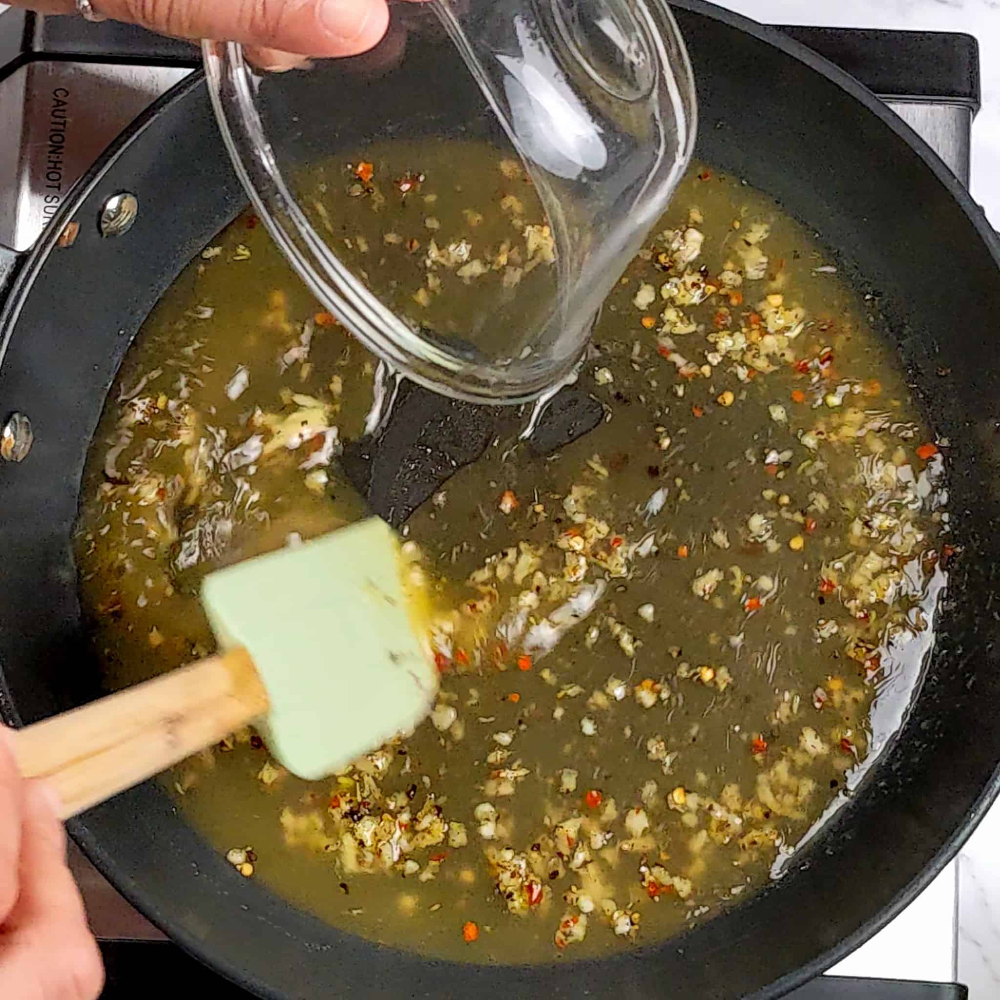 chicken brown added to the unfinished lemon pepper sauce in a frying pan with a silicone spatula