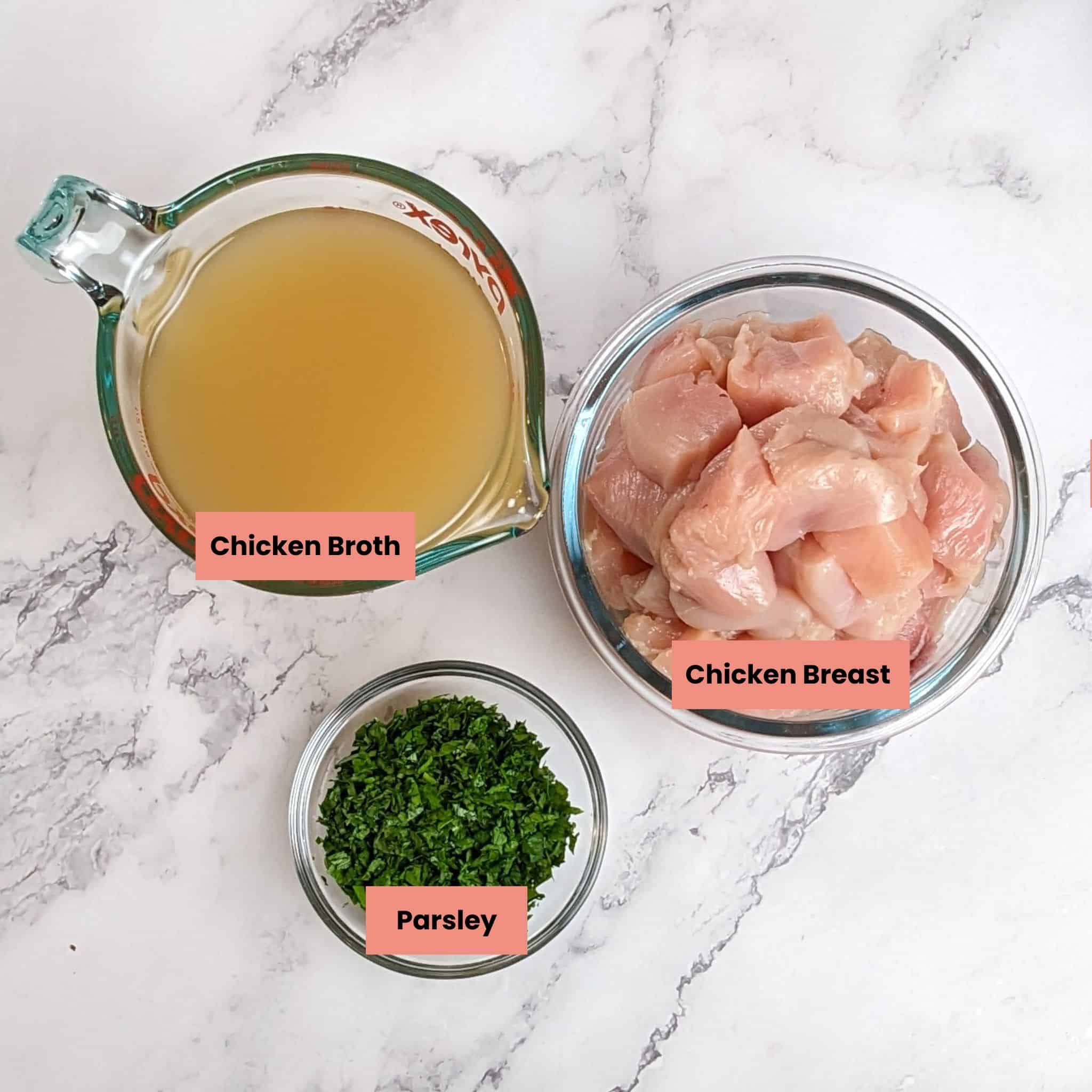 ingredients of diced chicken, chicken broth and chopped fresh parsley for the spicy calabrian chicken chowder in container of a marble counter