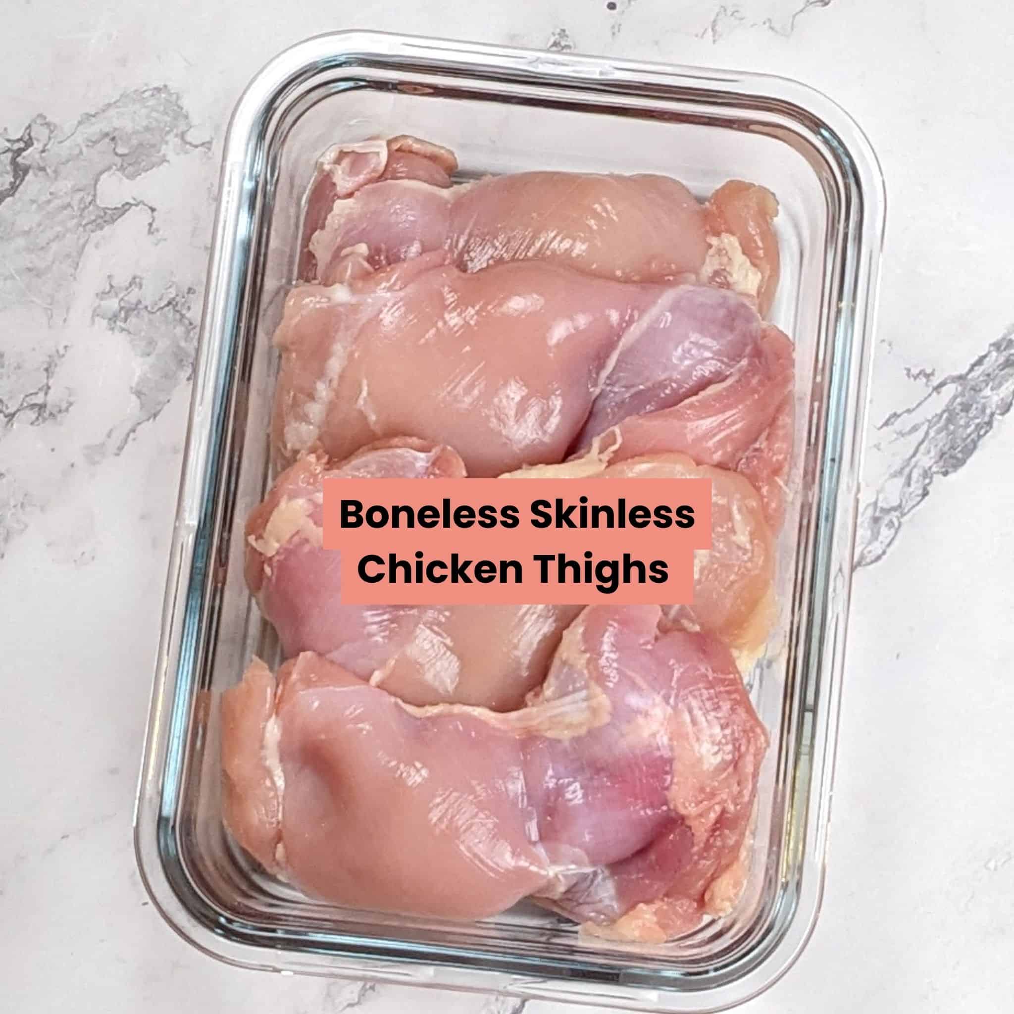 Boneless skinless chicken thighs cascaded in a rectangle glass container.