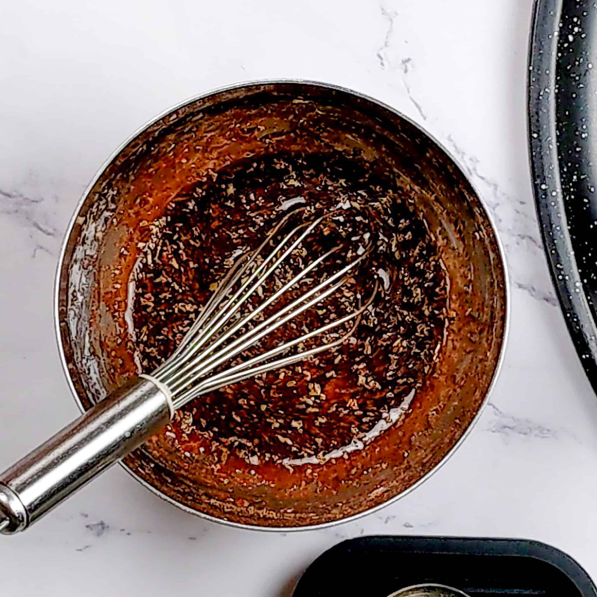 maple syrup mixture in a small metal mixing bowl with a small whisk