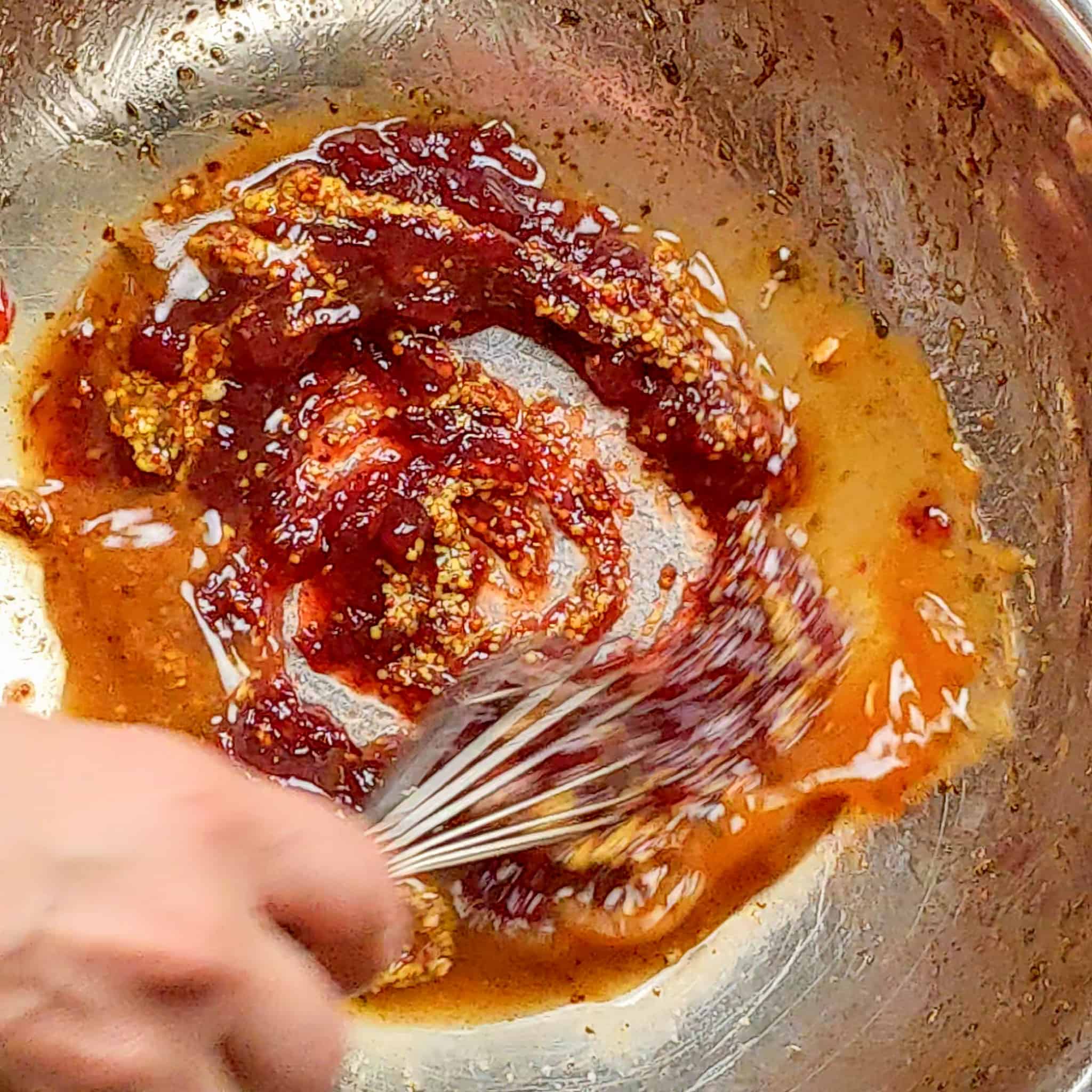 a whisk mixing the ingredients for the cranberry dressing