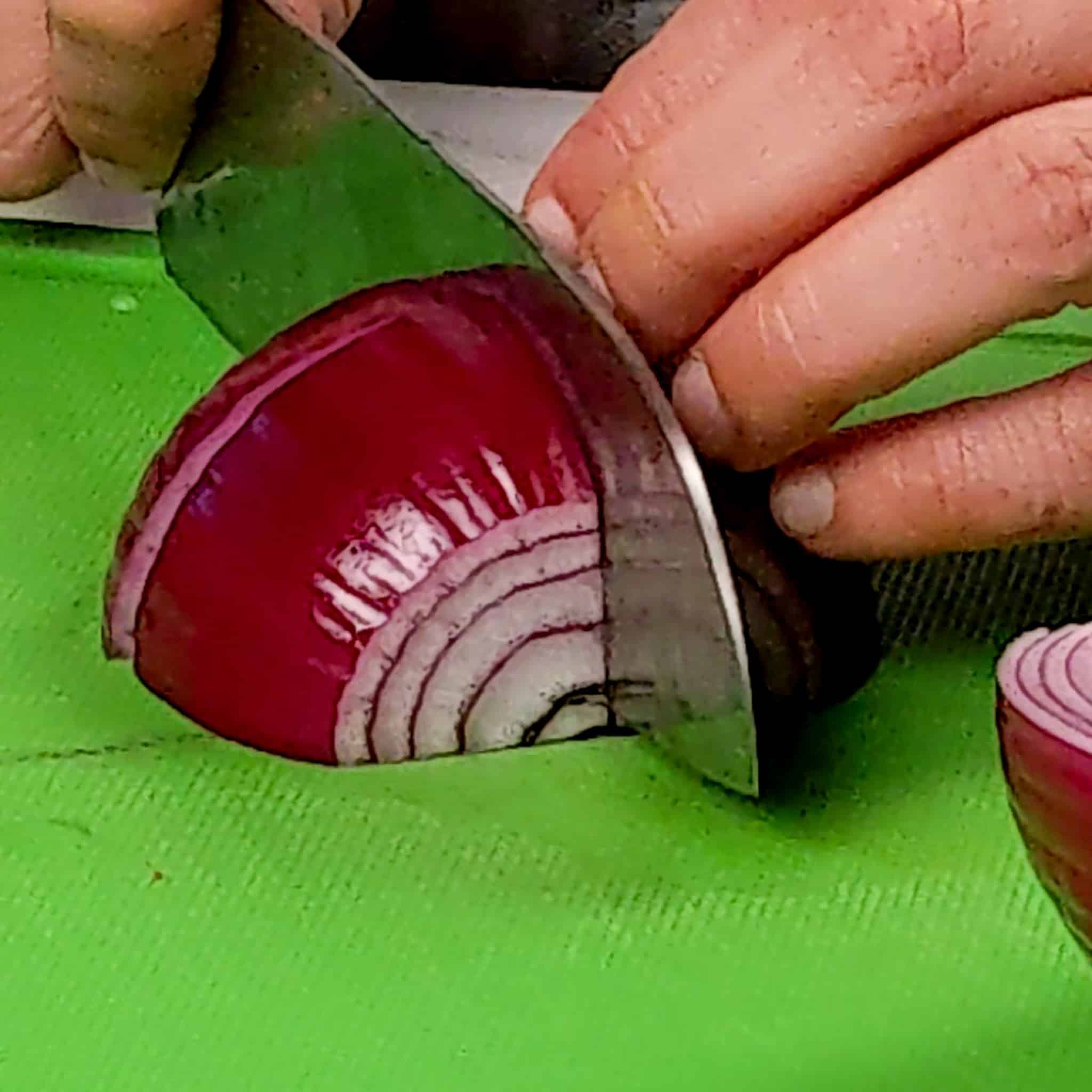 close up of cutting a quartered red onion