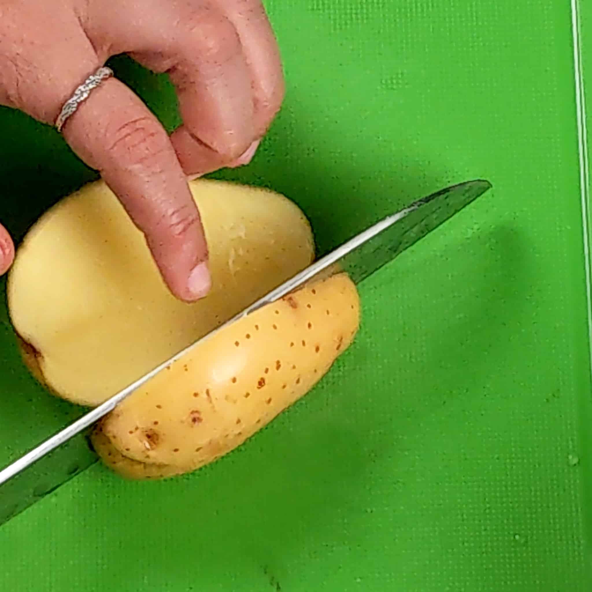 close up of a baby dutch yellow potato being cut in half on a cutting board