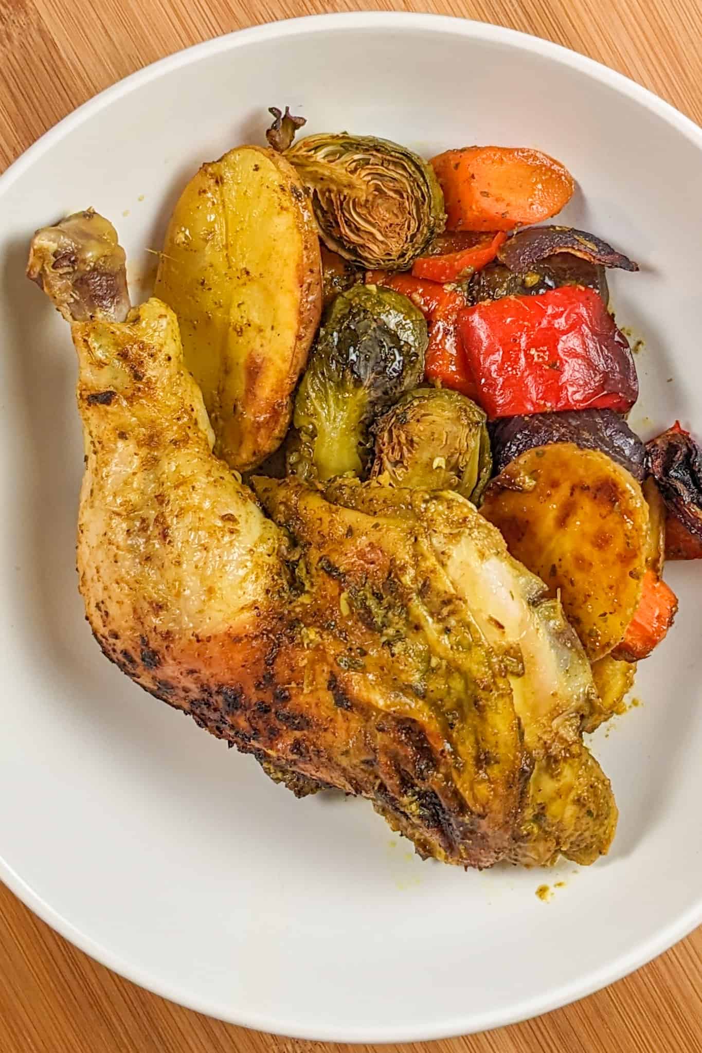 top view of the Curry spatchcocked chicken with vegetables plated in a large wide round bowl