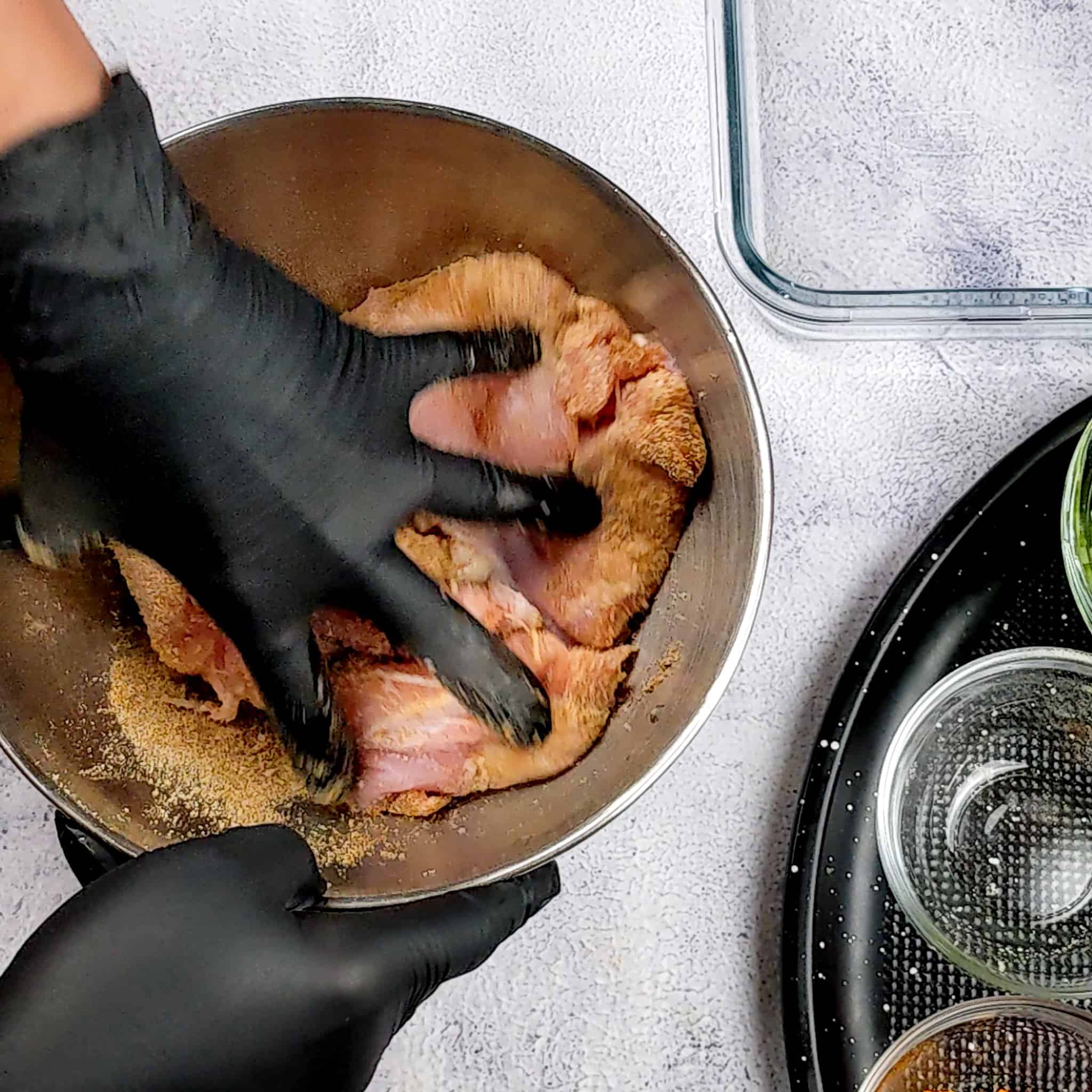 gloved hands messaging seasoning chicken thighs for the dill lentil chicken soup