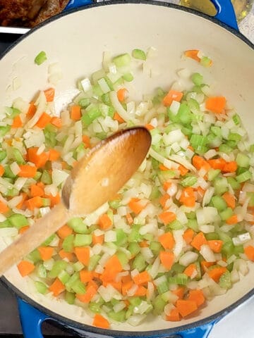 mirepoix of onion, carrots, and celery sweating in a Lodge 6 quart enameled Dutch oven