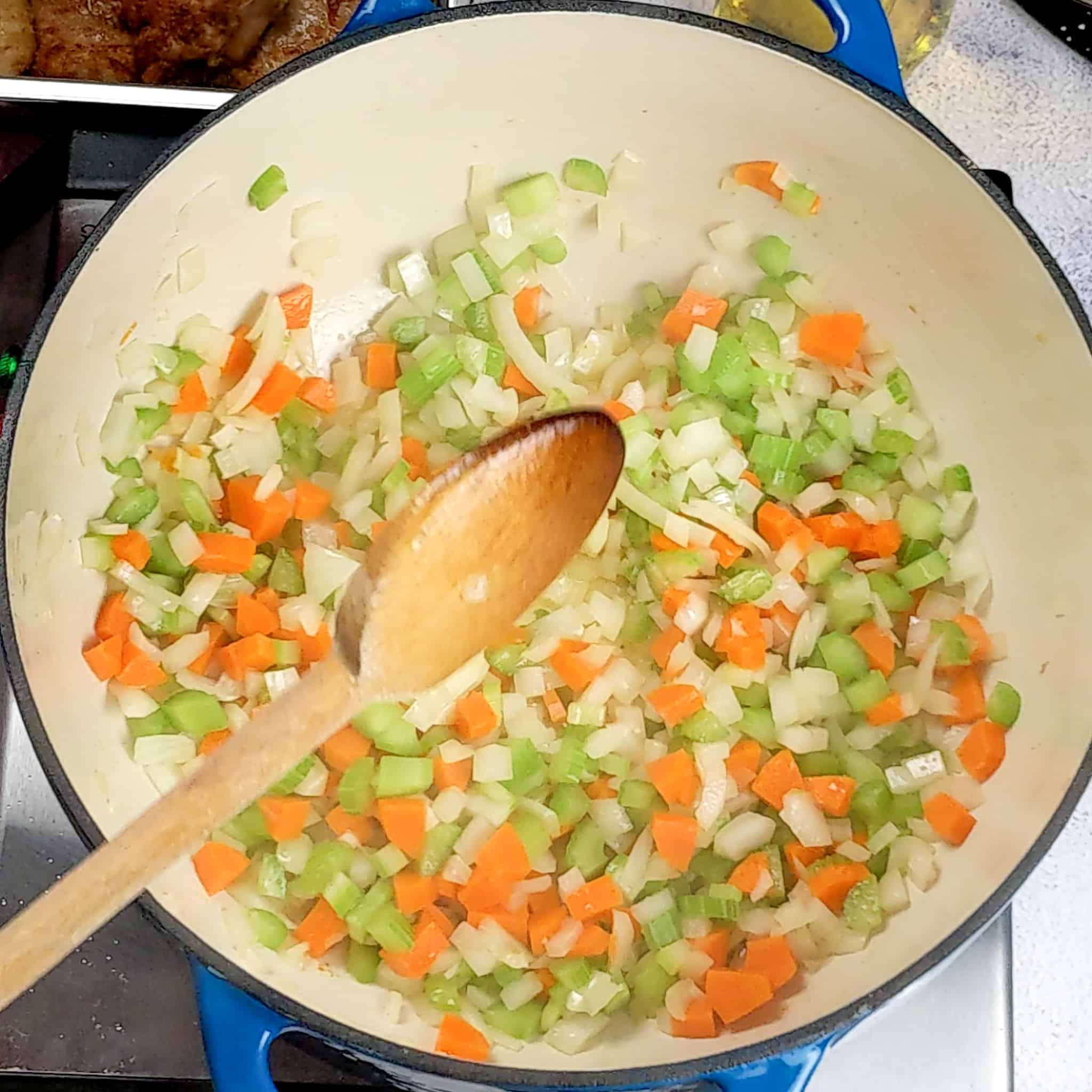 mirepoix of onion, carrots, and celery sweating in a Lodge 6 quart enameled Dutch oven