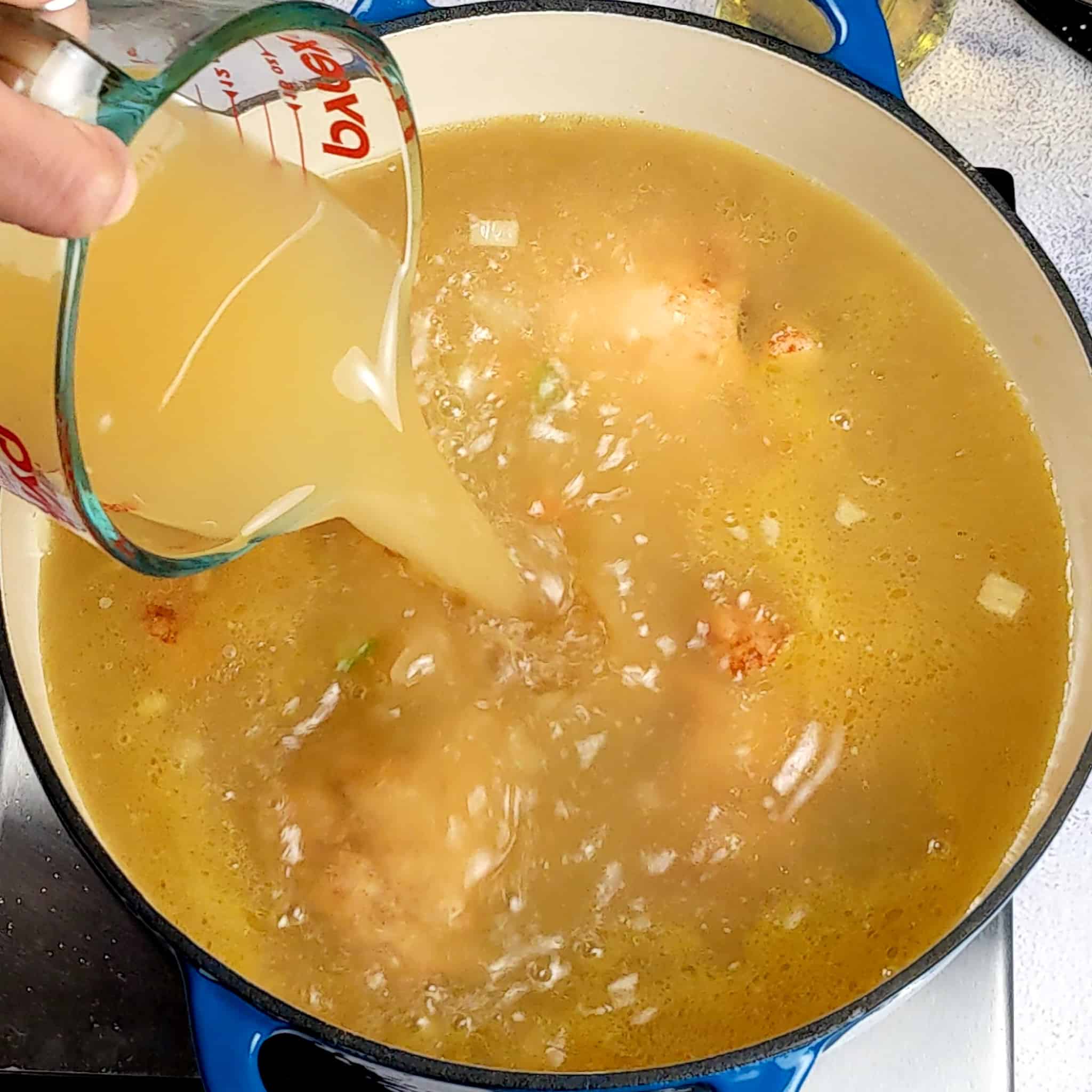 chicken broth being poured into the pot
