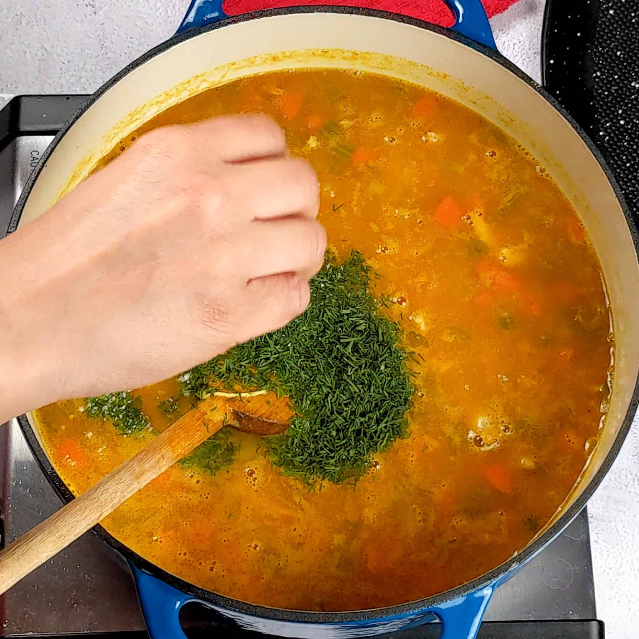 fresh chopped dill being added into the soup