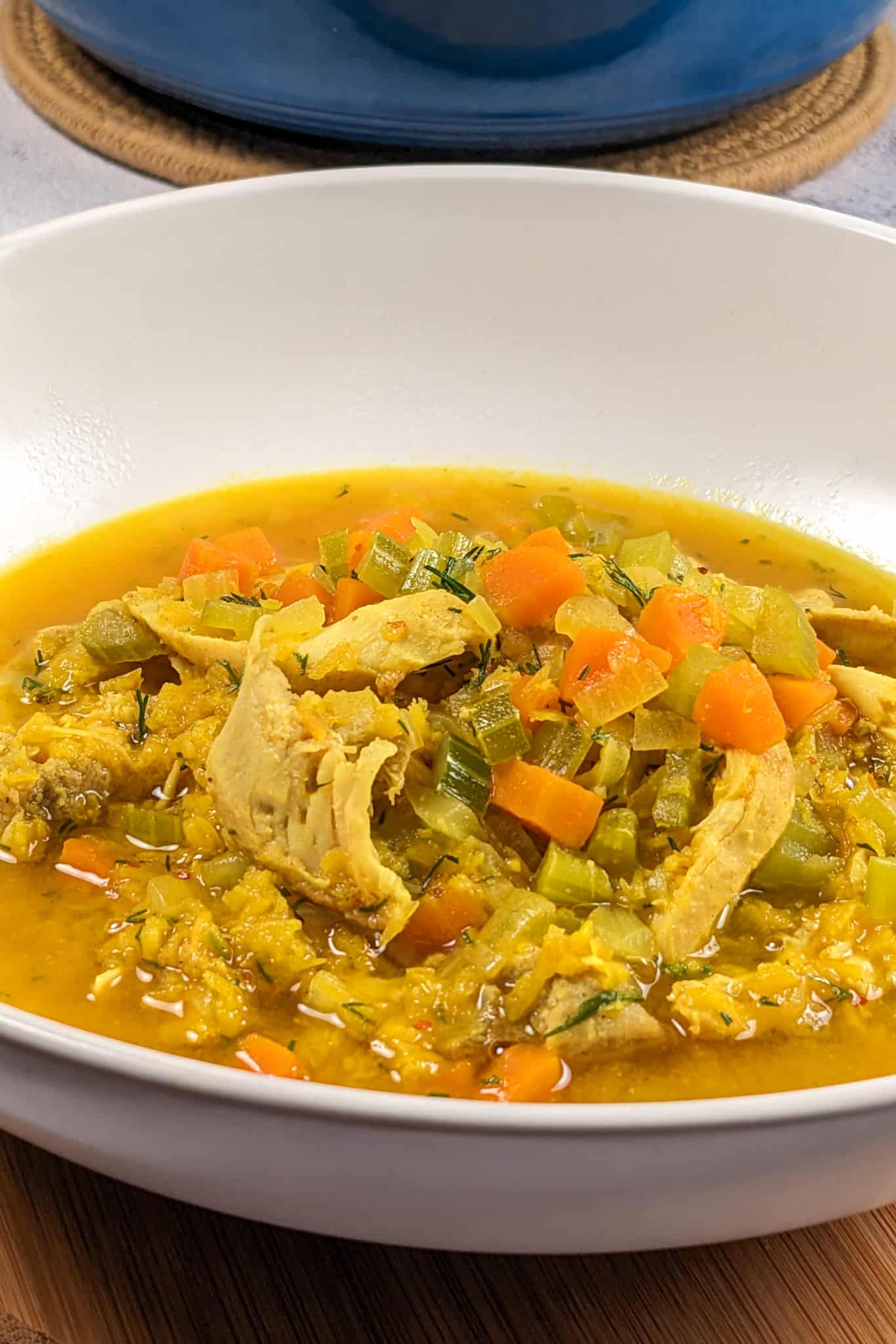 side view of the plated aleppo pepper spiced dill lentil chicken soup in a round wide bowl