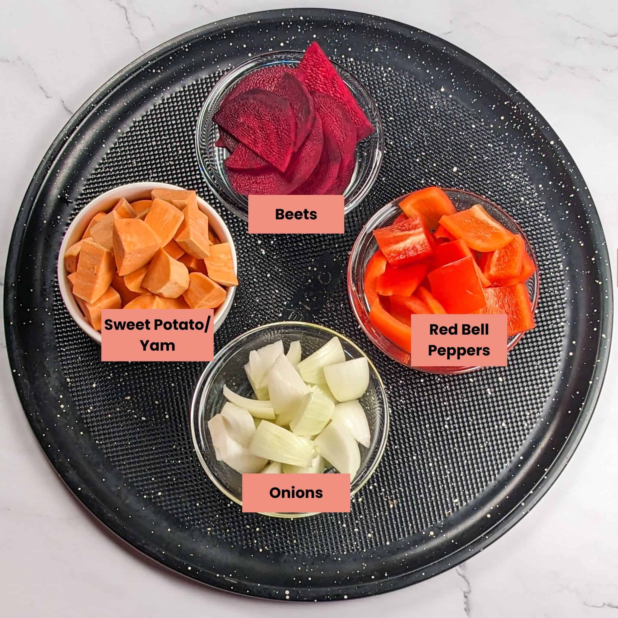 chopped root vegetables and onions in containers on a large round pizza pan