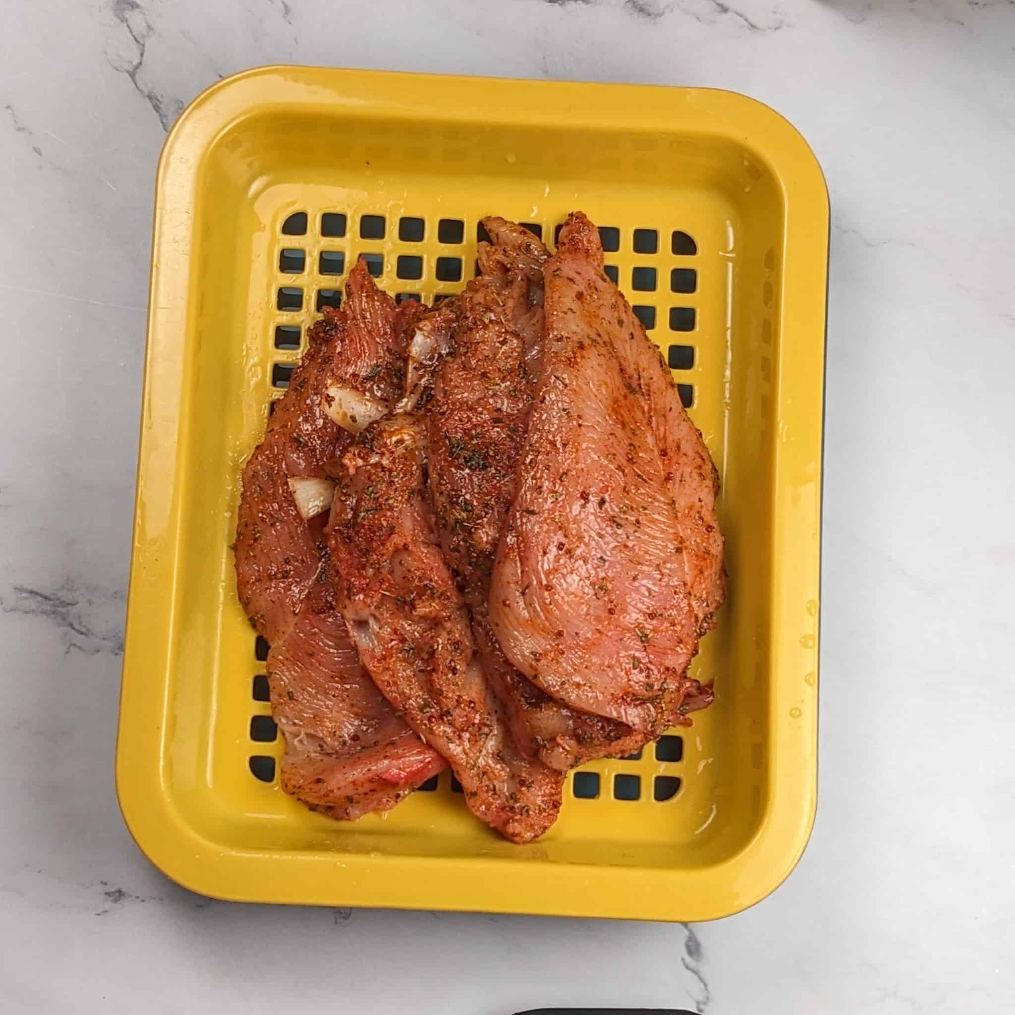 a drainage tray with butterflied chicken breast cascading horizontally