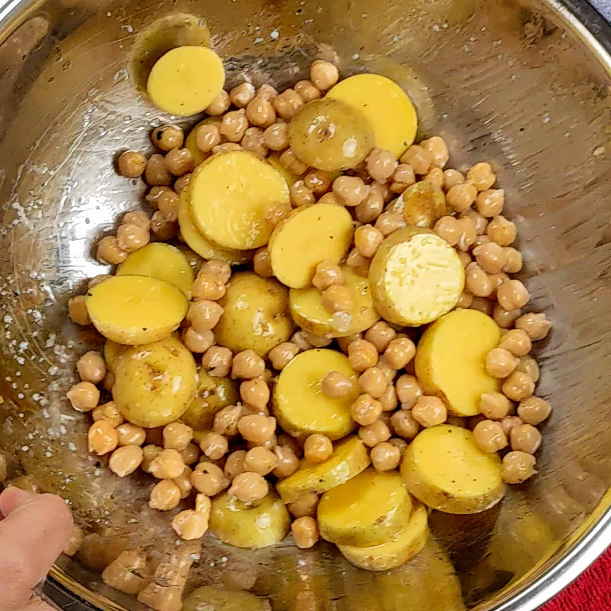 canned chickpeas and sliced baby Dutch potatoes tossed in avocado oil, salt and pepper in a stainless large mixing bowl