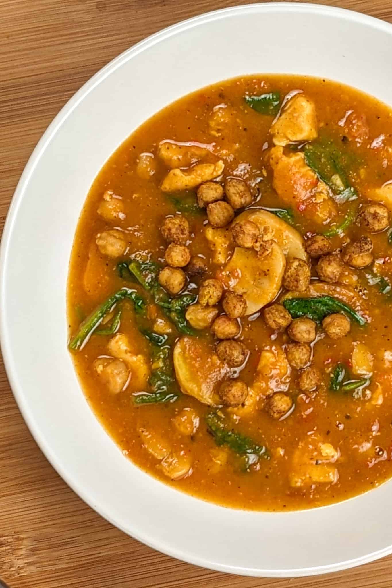 top view of Air Fryer Butternut Squash Spiced Chickpeas Chicken Soup in a round wide soup bowl on a wooden board