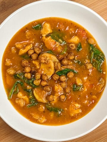 top view of Air Fryer Butternut Squash Spiced Chickpeas Chicken Soup in a round wide soup bowl on a wooden board