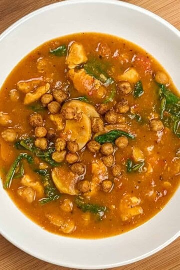 top view of Air Fryer Butternut Squash Spiced Chickpeas Chicken Soup in a round wide soup bowl on a wooden board